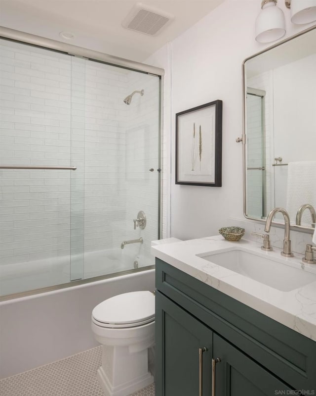 full bathroom featuring toilet, vanity, tile patterned floors, and shower / bath combination with glass door