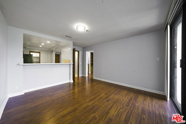 empty room featuring a textured ceiling and dark wood-type flooring