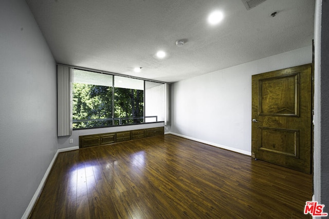 unfurnished room featuring a textured ceiling and dark hardwood / wood-style floors