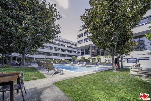 view of pool featuring a lawn and a patio