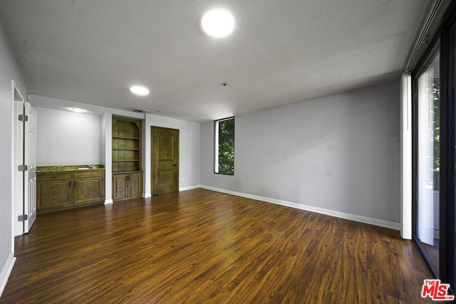 unfurnished room with a textured ceiling and dark hardwood / wood-style floors