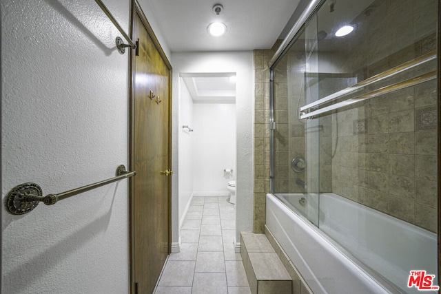 bathroom with bath / shower combo with glass door, toilet, and tile patterned floors