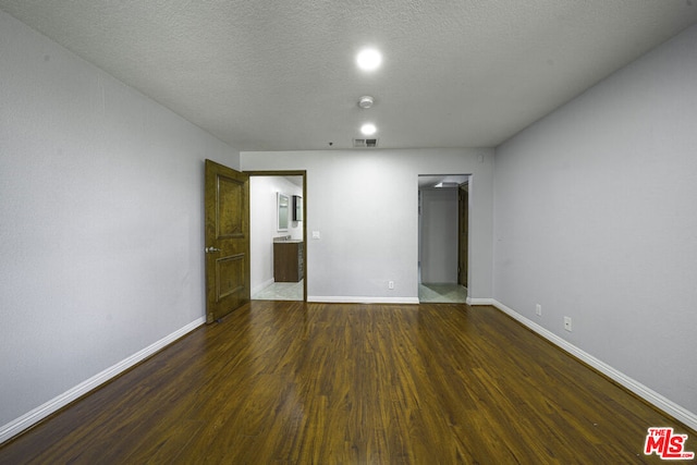 unfurnished bedroom featuring a textured ceiling and dark hardwood / wood-style flooring