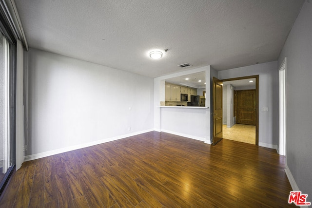 unfurnished living room with a textured ceiling and dark hardwood / wood-style floors