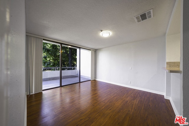 unfurnished room with a textured ceiling, dark wood-type flooring, and expansive windows