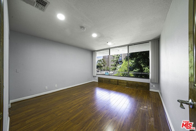 empty room with a textured ceiling and dark wood-type flooring