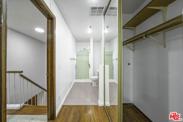 bathroom featuring hardwood / wood-style floors, toilet, and a shower with door