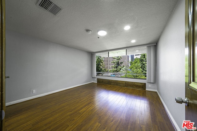 spare room with a textured ceiling and dark hardwood / wood-style flooring