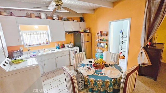 kitchen with white cabinetry, beamed ceiling, white gas stove, and washer / dryer