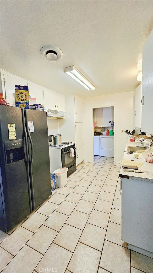 kitchen featuring separate washer and dryer, light tile patterned flooring, white cabinets, and black appliances