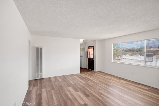 empty room featuring a textured ceiling and light wood-type flooring