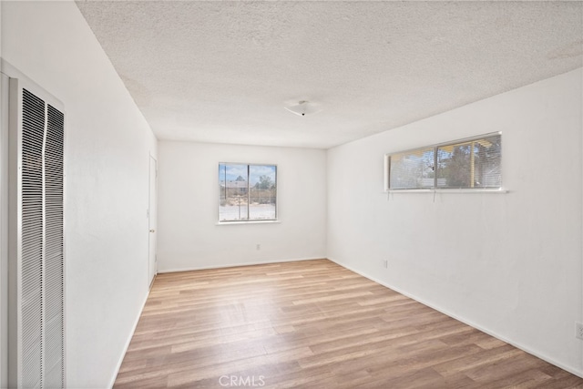 unfurnished room with a textured ceiling and light hardwood / wood-style flooring