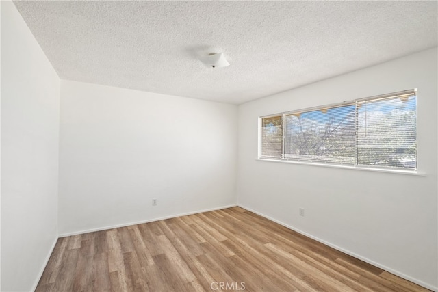 spare room featuring a textured ceiling and light hardwood / wood-style flooring