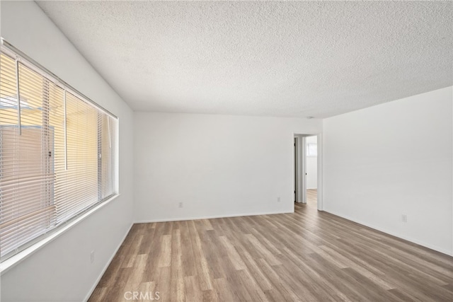 unfurnished room with a textured ceiling, light hardwood / wood-style flooring, and plenty of natural light