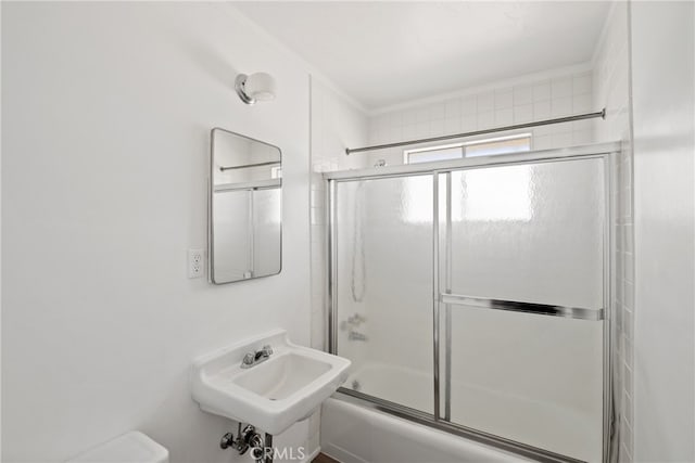 full bathroom with toilet, sink, and combined bath / shower with glass door