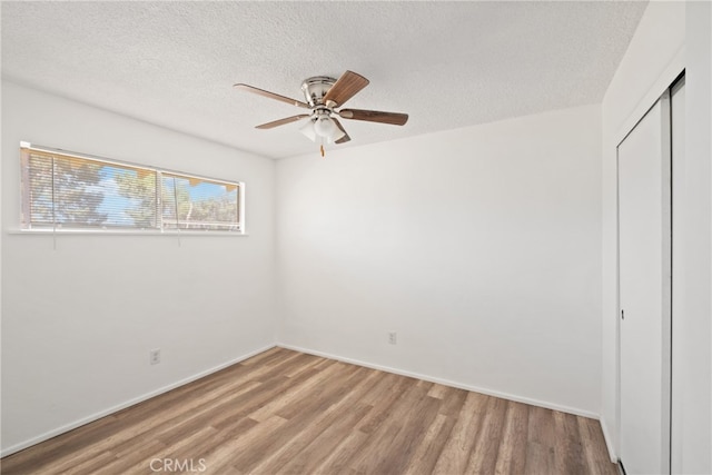 unfurnished bedroom featuring ceiling fan, a textured ceiling, a closet, and wood-type flooring