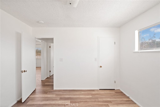 unfurnished room featuring light hardwood / wood-style floors and a textured ceiling