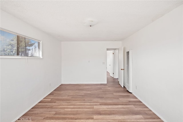 spare room featuring a textured ceiling and light hardwood / wood-style flooring