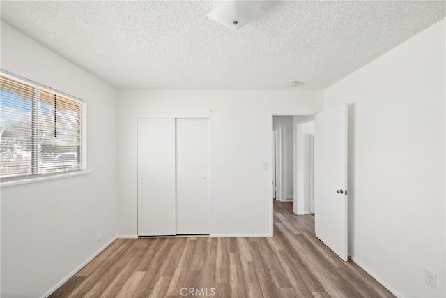 unfurnished bedroom featuring a textured ceiling, light hardwood / wood-style floors, and a closet