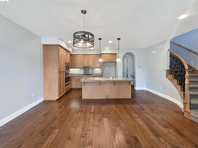 kitchen featuring sink, hanging light fixtures, dark wood-type flooring, a kitchen island with sink, and appliances with stainless steel finishes