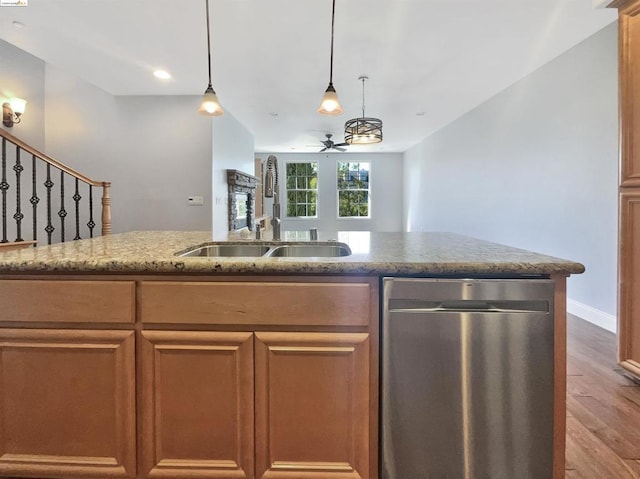 kitchen featuring ceiling fan, sink, light stone counters, stainless steel dishwasher, and hardwood / wood-style flooring