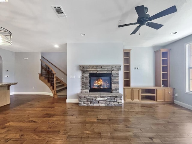 living room with ceiling fan, a stone fireplace, and dark hardwood / wood-style flooring