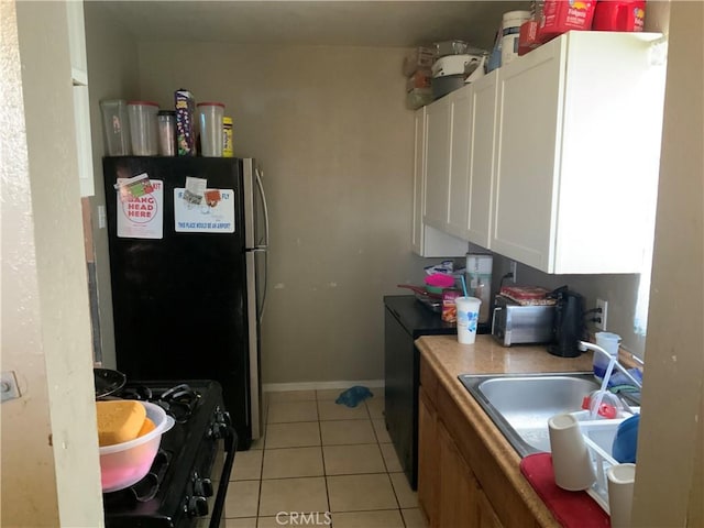 kitchen featuring white cabinets, black gas stove, sink, light tile patterned flooring, and stainless steel refrigerator