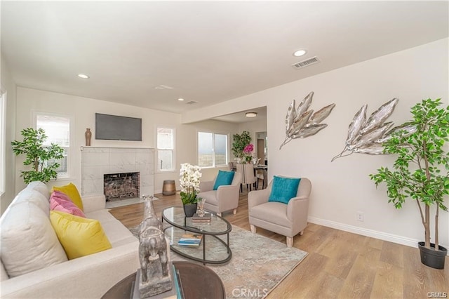 living room with a tile fireplace and light hardwood / wood-style floors