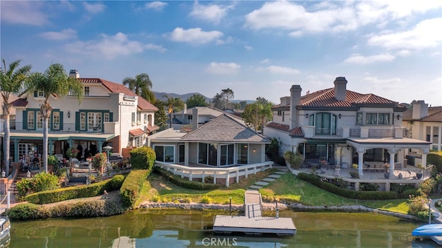 back of house featuring a balcony, a yard, and a water view