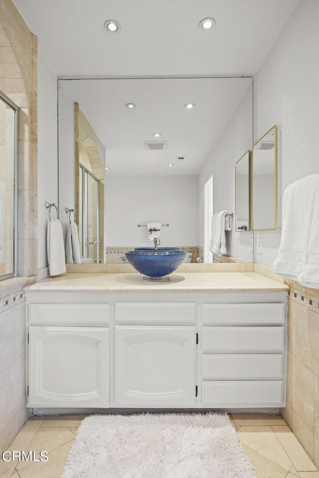 bathroom featuring walk in shower, tile walls, vanity, and tile patterned floors