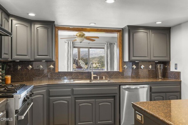 kitchen with ceiling fan, sink, backsplash, gray cabinets, and appliances with stainless steel finishes