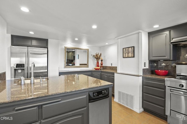 kitchen featuring light tile patterned floors, gray cabinetry, backsplash, stone counters, and stainless steel appliances