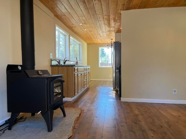 kitchen with stainless steel refrigerator, wood ceiling, hardwood / wood-style floors, and a wood stove