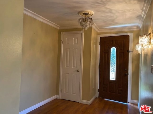 foyer with a notable chandelier, dark hardwood / wood-style floors, and crown molding