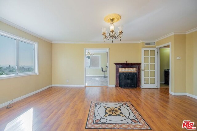 unfurnished living room with ornamental molding, light hardwood / wood-style flooring, and a notable chandelier