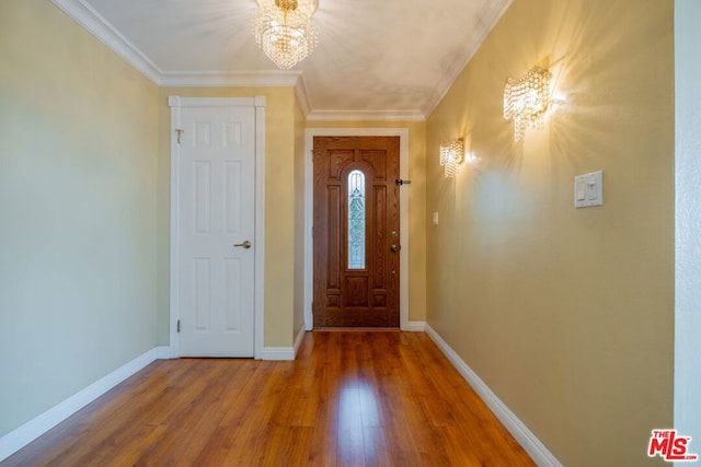 entryway with wood-type flooring, an inviting chandelier, and crown molding