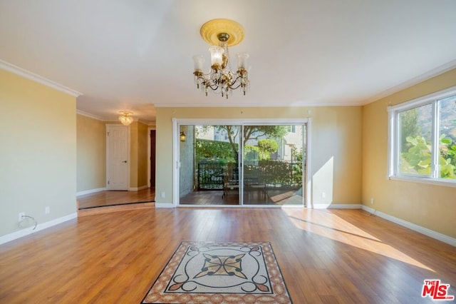 empty room with an inviting chandelier, wood-type flooring, and ornamental molding