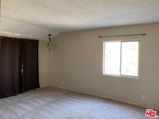 empty room featuring a textured ceiling, carpet floors, and lofted ceiling