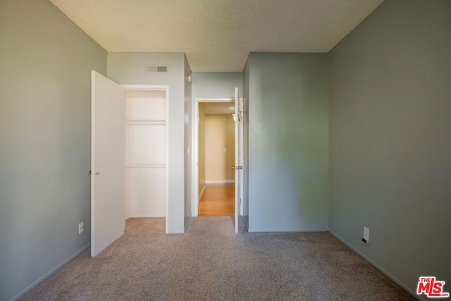 unfurnished bedroom featuring a textured ceiling and light carpet