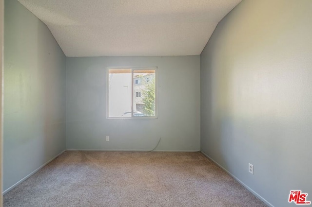 unfurnished room with a textured ceiling, light colored carpet, and vaulted ceiling