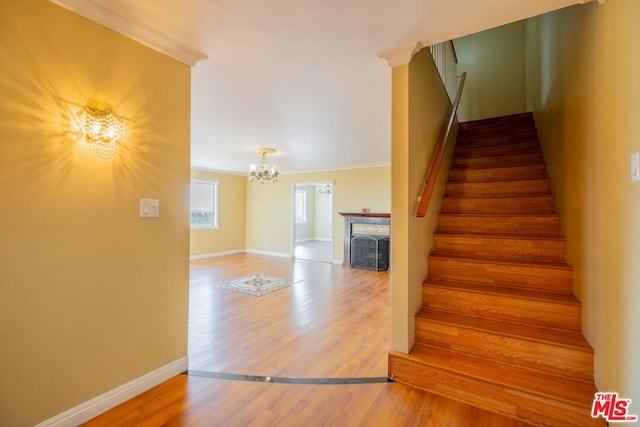 stairway with hardwood / wood-style floors, an inviting chandelier, and ornamental molding