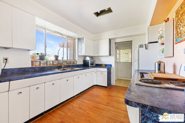 kitchen featuring stainless steel appliances, sink, light wood-type flooring, and white cabinets