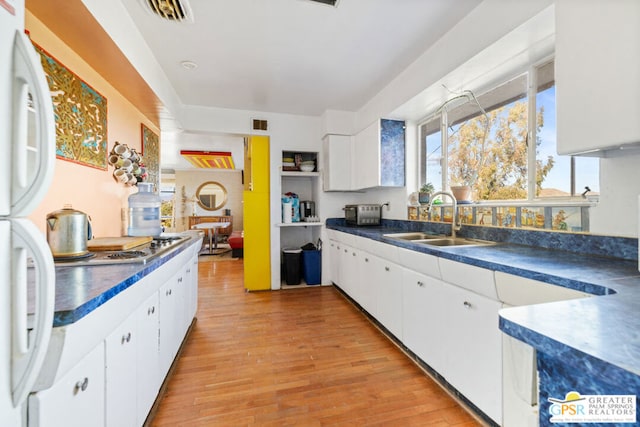 kitchen with light hardwood / wood-style floors, white cabinets, sink, and white refrigerator