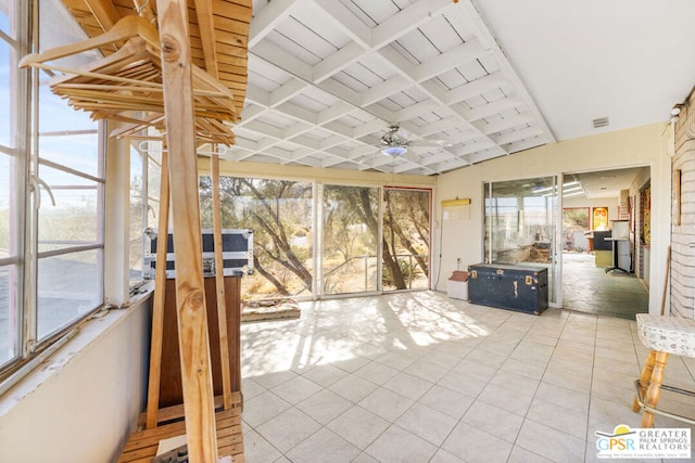 unfurnished sunroom featuring ceiling fan, lofted ceiling with beams, and plenty of natural light