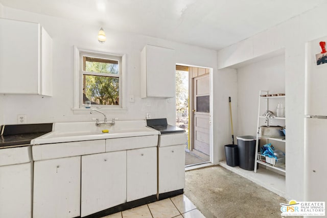 kitchen featuring white cabinets, sink, and light tile patterned floors