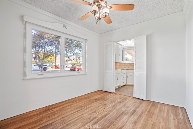 unfurnished bedroom featuring ensuite bathroom, light hardwood / wood-style flooring, a textured ceiling, and ceiling fan