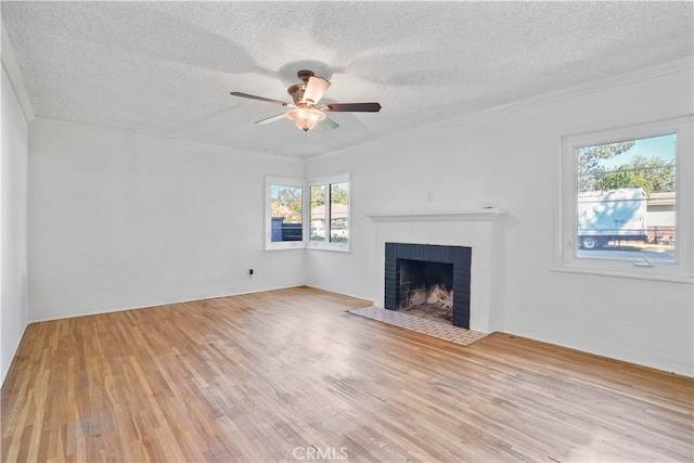 unfurnished living room with a textured ceiling, a fireplace, light hardwood / wood-style floors, and a wealth of natural light