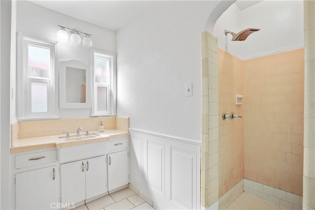 bathroom with a tile shower, tile patterned flooring, and vanity