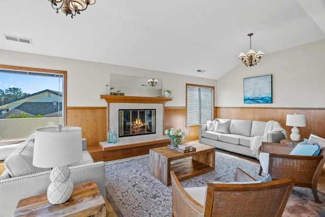 living room with lofted ceiling, a chandelier, and wood walls