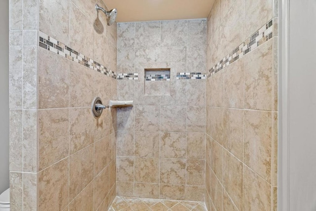 bathroom featuring tiled shower and toilet